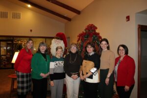 A small group of women gathered in front of a Santa Claus statue at the reception of Annette Thurston's retirement.